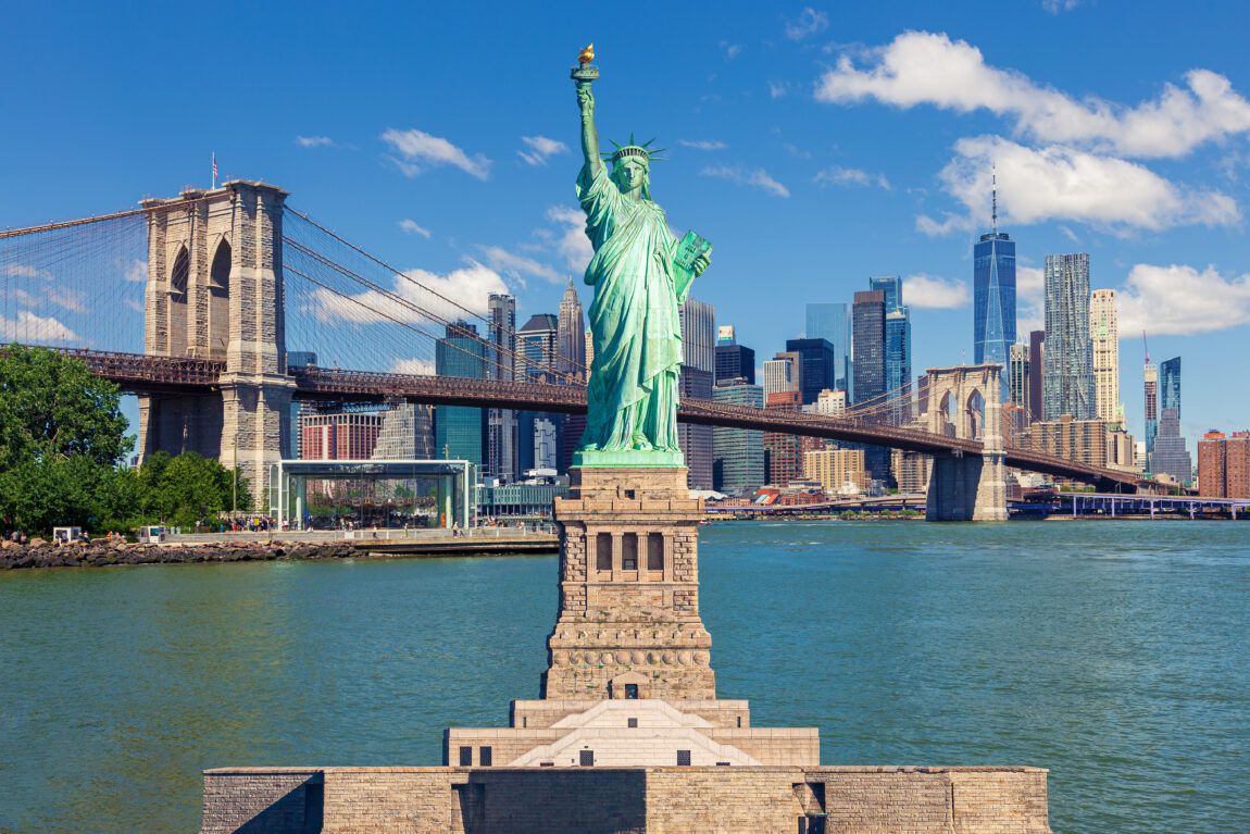 Statue of Liberty and New York City Skyline with Brooklyn Bridge, Manhattan High-Rises and World Trade Center.