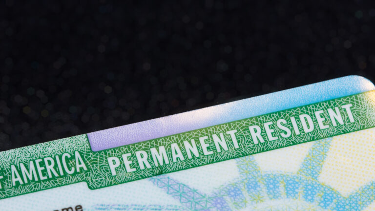 The most current version of the Green Card issued by USCIS as of October 2022. Bokeh pearls from reflecting light in the background. Ample negative copy space for text or additional design.