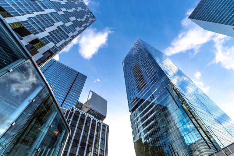 Low angle of modern highrise building with reflection glass in the city wth blue sky