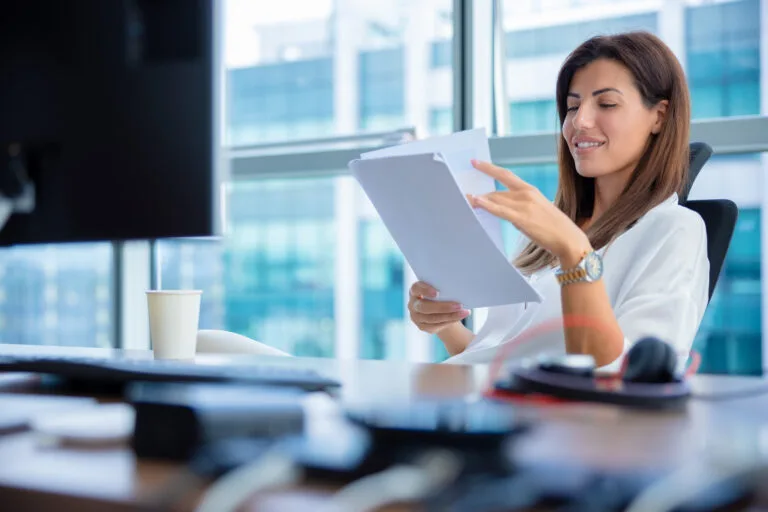 Beautiful businesswoman reading report in positive mood